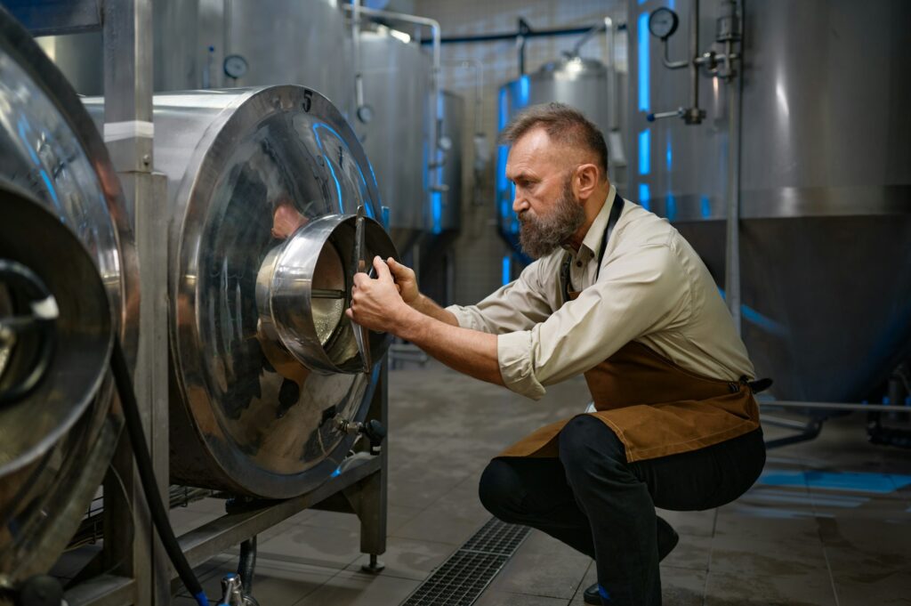 Concentrated brewer working with metallic vats in industrial brewery