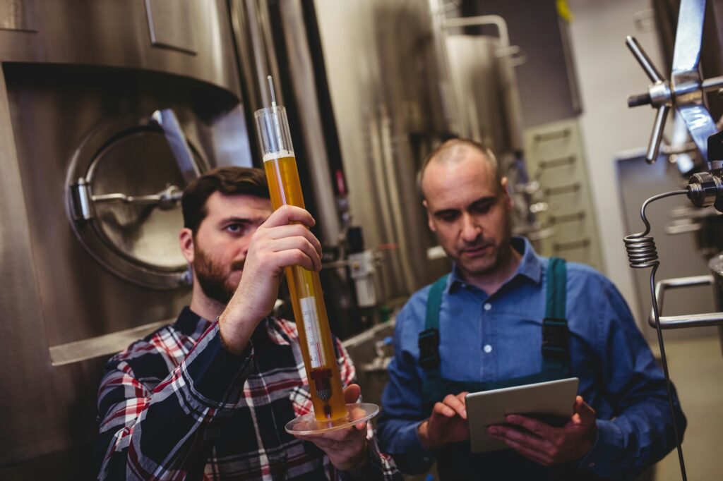 Owner inspecting beer in tube at brewery