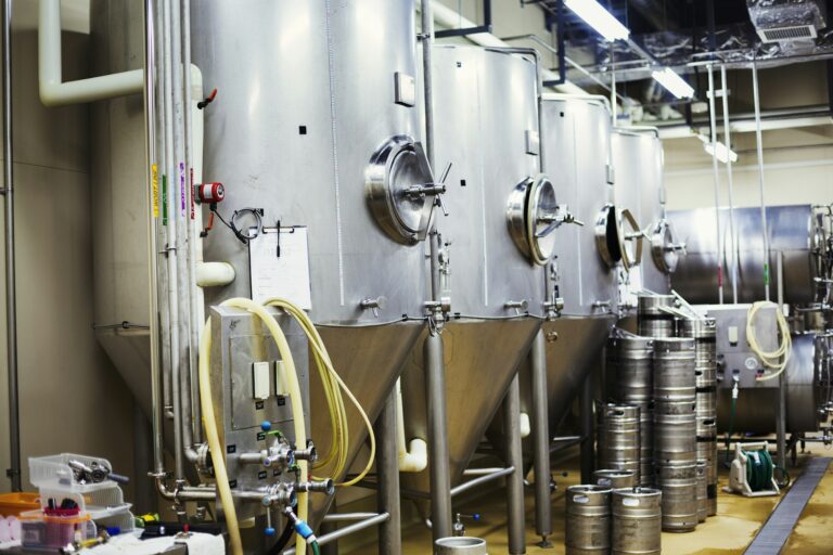 Row of large metal beer tanks in a brewery.